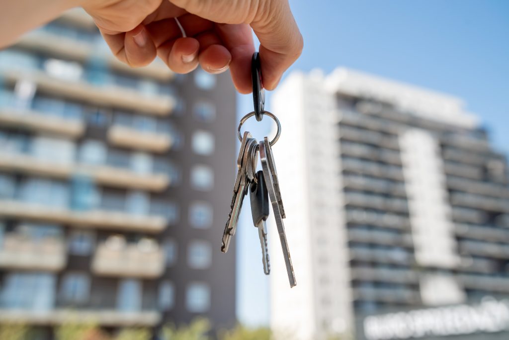 A person is currently holding a large bunch of keys right in front of a tall building